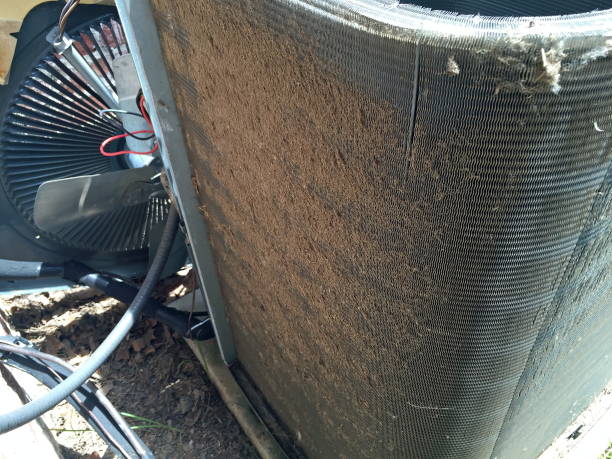 Dirty condenser coil fins on a home air conditioner compressor in need of cleaning and maintenance by technician.